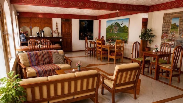 Amplia sala de estar con sofá, sillas, mesa de comedor y cocina al fondo.