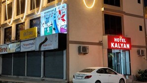 A multi-story building with a prominent 'HOTEL KALYAN' sign, air conditioning units, and a white car parked in front. - HOTEL KALYAN (Rajkot)