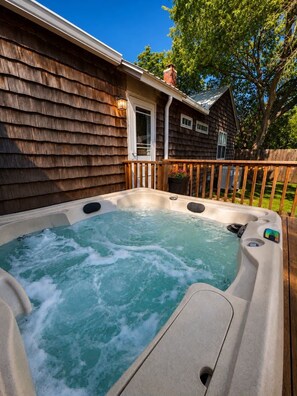 A hot tub in a backyard with a wooden deck and a house in the background. - Courtyard Cottage, Walk to Main Street, Hot tub! (Fredericksburg)