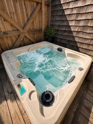 Ein Whirlpool mit Bedienfeld, umgeben von Holzterrassen und einem Holzzaun.