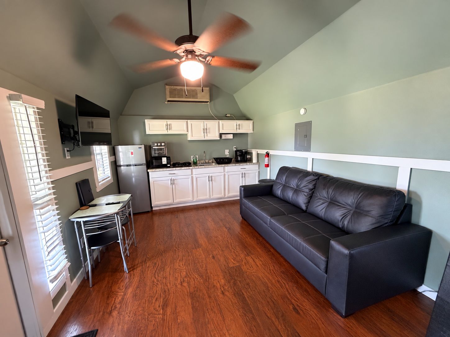 Un espacio habitable compacto con kitchenette, comedor y zona de estar.