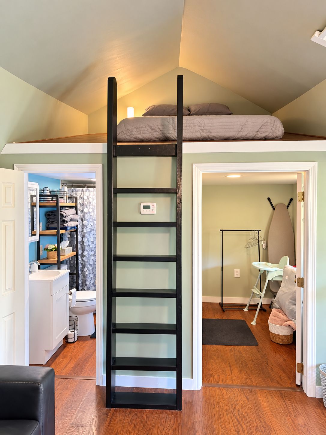 Slaapkamer in loftstijl met een zwarte ladder, een stapelbed, een inloopkast en een verschoningstafel voor baby's.
