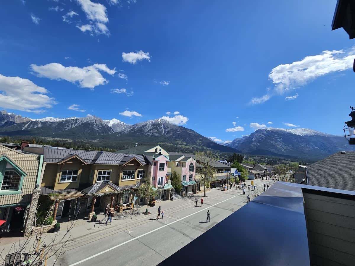 Une ville avec des bâtiments qui bordent une rue, une montagne en arrière-plan et un ciel dégagé.