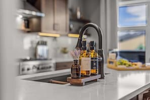 A kitchen with a modern faucet, a wooden cutting board, and two bottles of dish soap. - BRAND NEW Luxury Downtown Condo Settlers on Main (Canmore)
