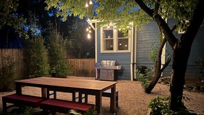A wooden deck with a bench, a barbecue grill, and string lights. - Gorgeous Zilker Cottage - Monthly Rental - Available August (Austin)