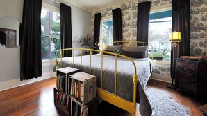 A bedroom with a bed, a bookshelf, a window with curtains, and a lamp. - Gorgeous Zilker Cottage - Monthly Rental - Available August (Austin)