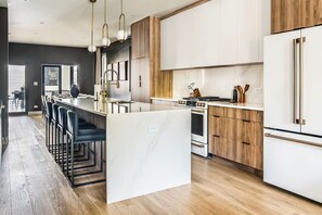 Een moderne keuken met een centraal eiland, houten kasten en roestvrijstalen apparatuur.