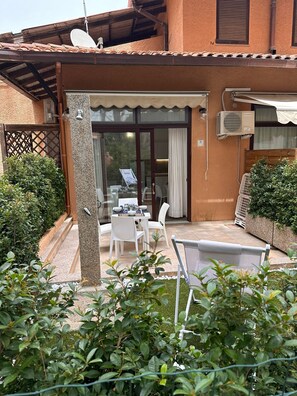 Eine Terrasse mit Tisch und Stühlen, eine Glastür zu einem Innenbereich und eine Satellitenschüssel auf dem Dach.