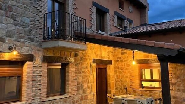 Un edificio de piedra con un balcón, mobiliario exterior y un patio bien iluminado.