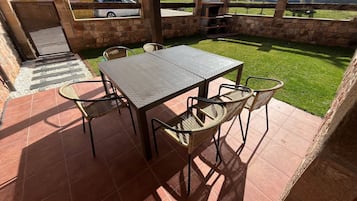 Un patio exterior con mesa y sillas, un muro de piedra y vistas al campo.