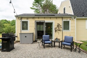 A house with a patio area featuring a grill, a gray storage unit, and two blue chairs. - Hidden Gem Near Wiscasset Village & Coast (Wiscasset)