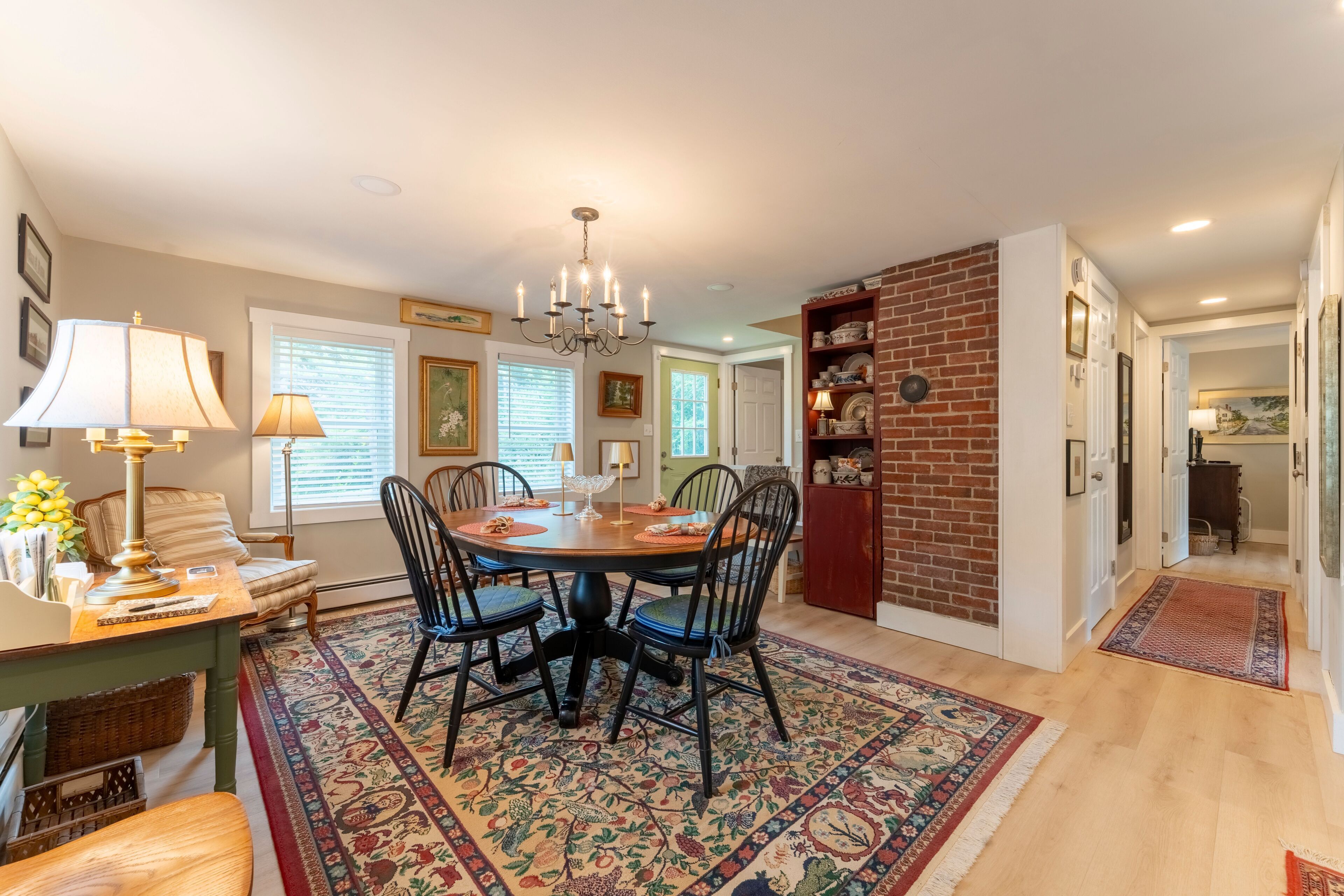 A dining area with a round table, chairs, a chandelier, and a patterned rug.
