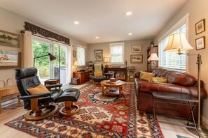A living room with a leather sofa, a coffee table, and a patterned rug. - Hidden Gem Near Wiscasset Village & Coast (Wiscasset)