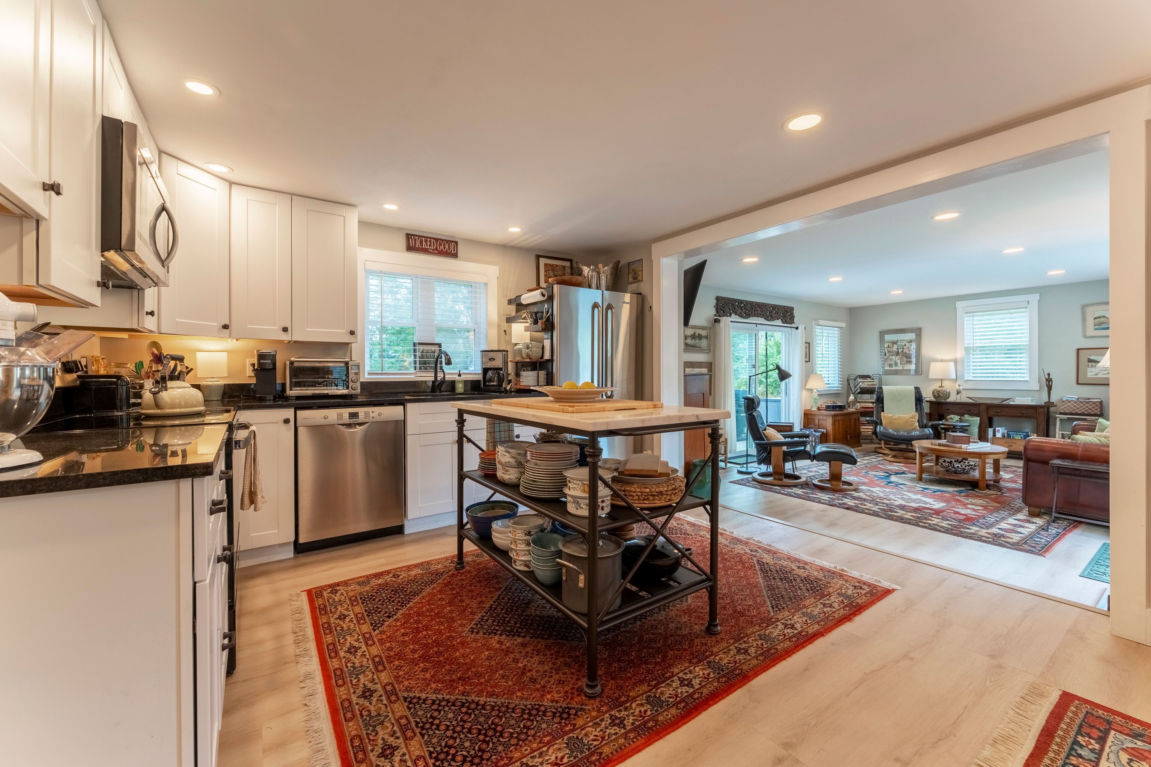 A modern kitchen with white cabinets, a stainless steel dishwasher, and a built-in oven.