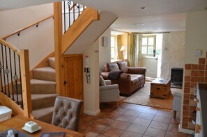 A living room with a staircase, a fireplace, and a dining area.