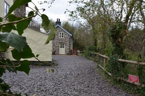 Een stenen cottage met een grindpad dat leidt naar een houten poort.