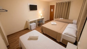 Habitación de hotel con dos camas, un escritorio, televisión y zona de ducha.