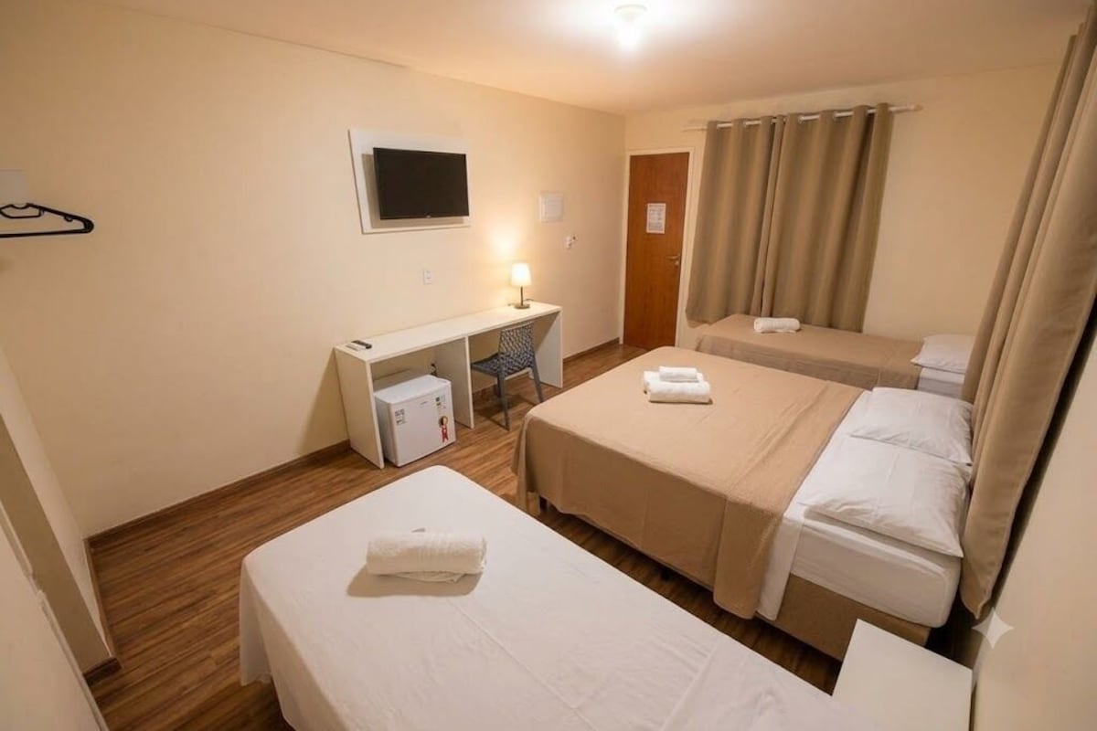 Une chambre d’hôtel avec deux lits, un bureau, une télévision et un espace douche.