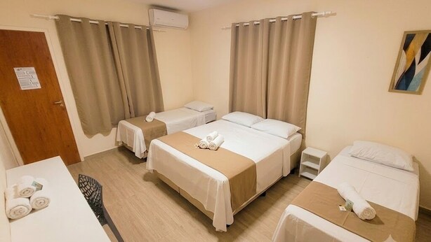 Habitación de hotel con dos camas individuales, una mesita con toallas, una silla y una puerta.