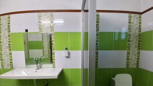 Une salle de bain avec un lavabo, un miroir, des toilettes et des murs recouverts de carreaux verts.