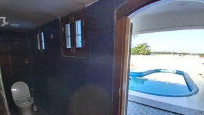 Une salle de bain avec des toilettes, une petite fenêtre et une vue sur une piscine extérieure.