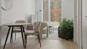 Un interior moderno con comedor, sofá, planta en maceta y vistas a través de una ventana.