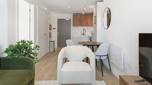 Una sala de estar moderna con un sofá, una butaca, una mesita y una planta.