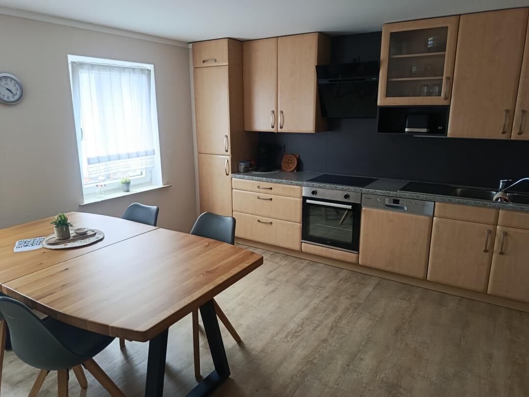 A kitchen with wooden cabinets, a stove, and a dining table with chairs.