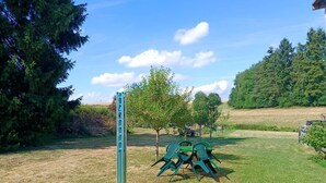 A grassy outdoor area with a metal structure, a small tree, and a metal table with chairs. - NEW! To the Old Inn (Reich)