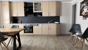 A modern kitchen with wooden cabinets, a dining table, and chairs. - NEW! To the Old Inn (Reich)