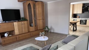 A living room with a sofa, TV, wooden cabinet, and a small round table with a plant. - NEW! To the Old Inn (Reich)