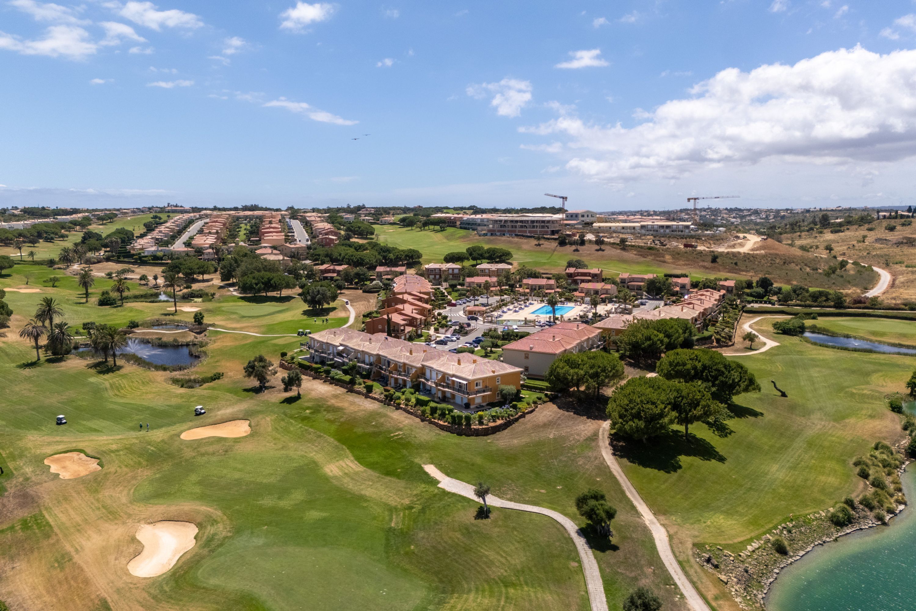Un campo de golf con un club de campo, una piscina y vistas del paisaje circundante.