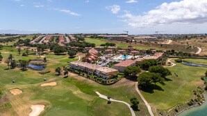 Un campo de golf con un club de campo, una piscina y vistas del paisaje circundante.