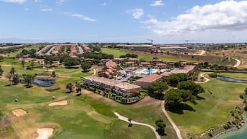 Un campo de golf con un club de campo, una piscina y vistas del paisaje circundante.