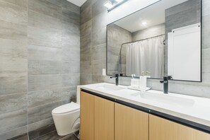 Ein modernes Badezimmer mit einem großen Spiegel, zwei Waschbecken und einer Toilette.