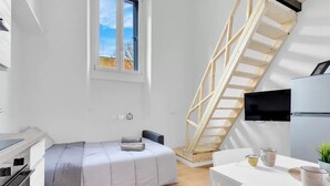 Habitación compacta con cama, una mesita, televisión y ventana con vistas.