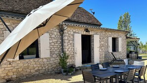 A stone house with a gravel patio, outdoor seating, and a pergola. - Le Clos des Pères House: 120 m², 3 bedrooms, 2 bathrooms, fenced-in yard. Pets allowed (Monflanquin)
