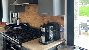 A modern kitchen with a gas stove, coffee machine, toaster, and wooden backsplash. - Le Clos des Pères House: 120 m², 3 bedrooms, 2 bathrooms, fenced-in yard. Pets allowed (Monflanquin)