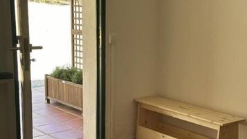 Una habitación con un banco de madera, una puerta que da al exterior y piso de baldosas.