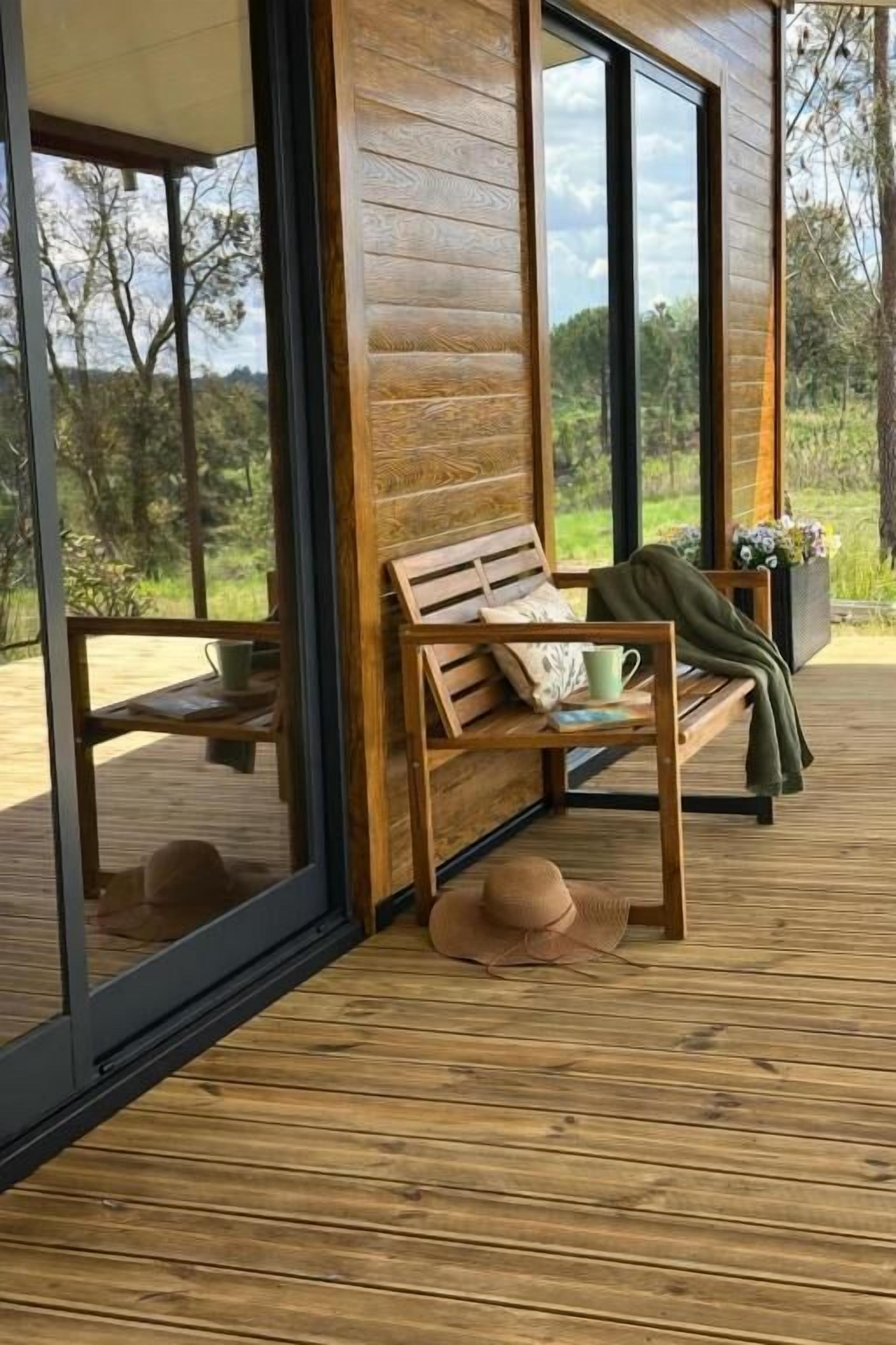 Terraza de madera con un banco, un sombrero y una planta en maceta.