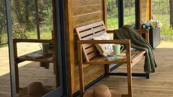 Terraza de madera con un banco, un sombrero y una planta en maceta.