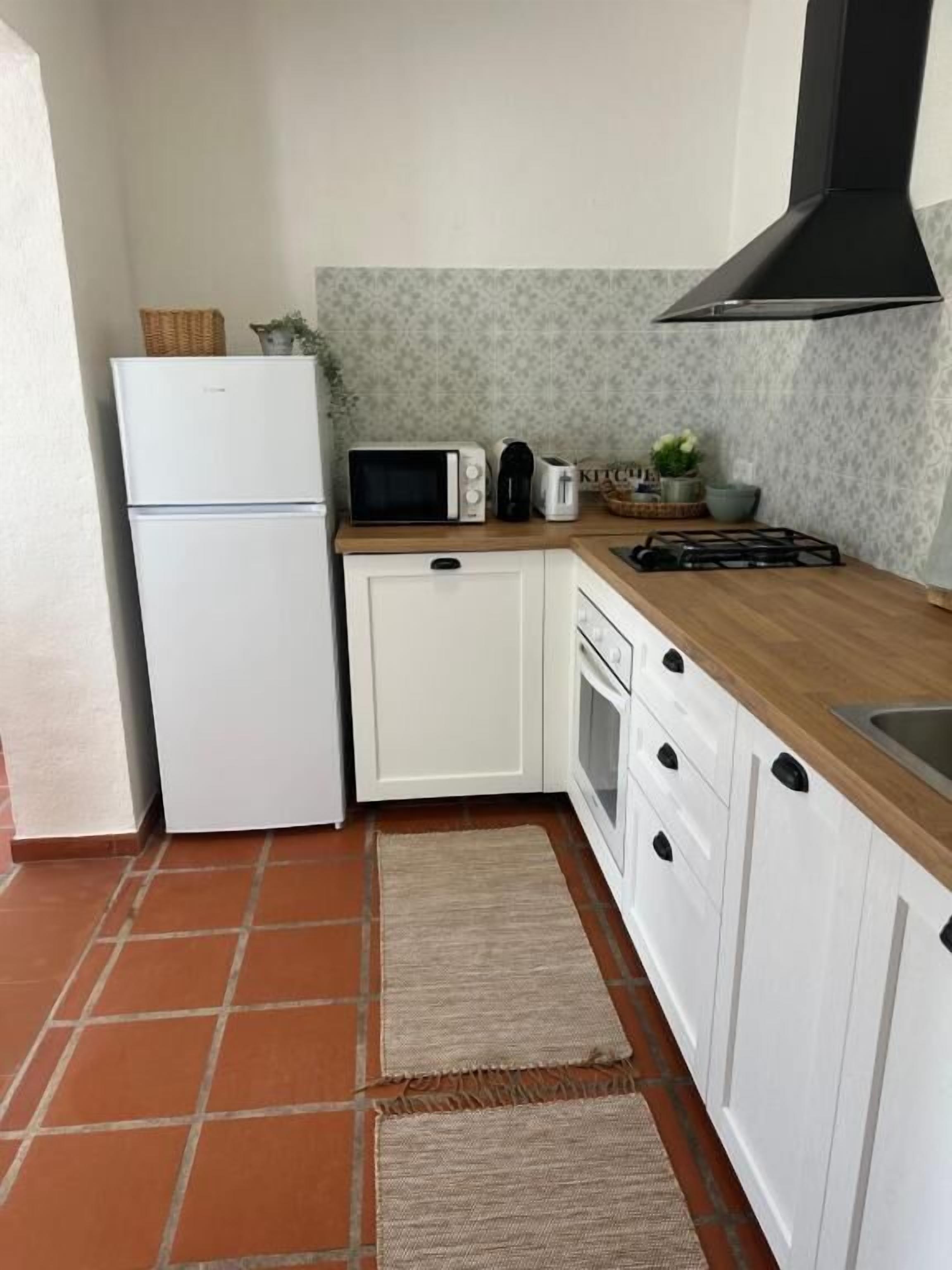 A compact kitchen with white cabinets, a microwave, a toaster, and a gas stove.