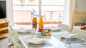 Una mesa de comedor con individuales, platos, vasos y una bandeja de frutas.