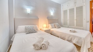 Habitación de hotel con dos camas, una mesita de noche, una lámpara y un armario con puertas empaneladas.