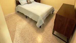 Ein Schlafzimmer mit einem Bett, einem Schreibtisch, einem Deckenventilator und zwei Fenstern mit Jalousien.
