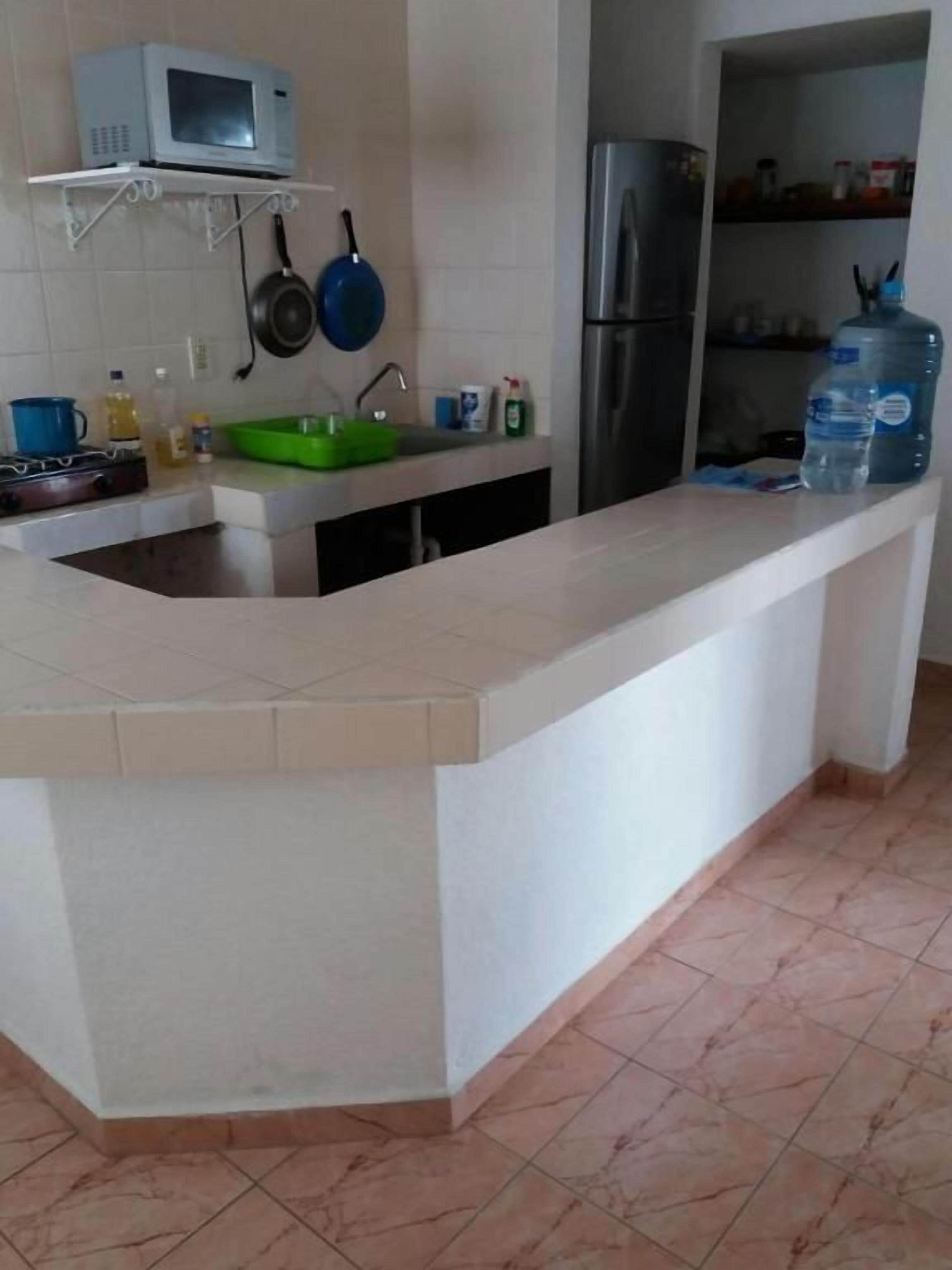 A kitchen with a white countertop, a sink, a microwave, a stove, and a refrigerator.