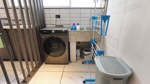 A laundry area with a washing machine, a mopping bucket, and a trash bin. - Bright 3BR Oasis • 500Mbps WiFi & 24/7 Security (Medellín)
