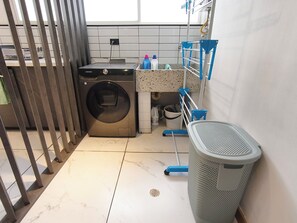 A laundry area with a washing machine, a mopping bucket, and a trash bin. - Bright 3BR Oasis • 500Mbps WiFi & 24/7 Security (Medellín)