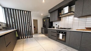 A modern kitchen with a marble floor, dark cabinetry, and a central island. - Bright 3BR Oasis • 500Mbps WiFi & 24/7 Security (Medellín)