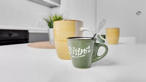 Eine Küchenarbeitsplatte mit zwei Tassen, eine grün, eine gelb, und jeweils ein Löffel.